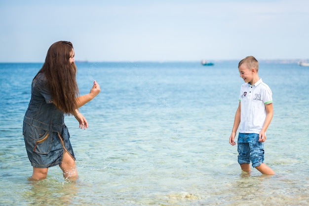 Madre e figlio di famiglia felici in piedi di fronte al mare in estate