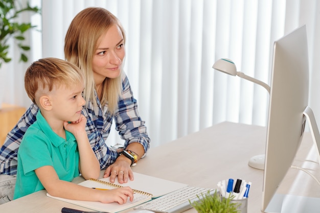 Madre e figlio guardano video educativi e completano le attività insieme alla scrivania