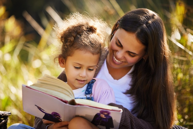 Madre e figlio leggere un libro in natura amore e legame per connettersi in infanzia al giardino mamma figlia e rilassarsi a picnic all'aperto per la pace o l'istruzione apprendimento e narrativa per la narrazione