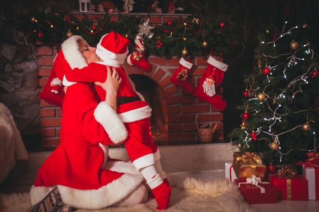 Madre e figlio nella stanza di Natale con albero decorato e camino