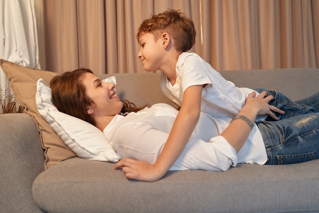 Madre e figlio sdraiato sul divano mentre si abbracciano
