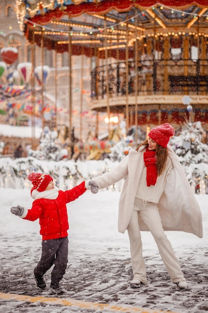 Madre e figlio si divertono al mercatino di Natale sullo sfondo della giostra