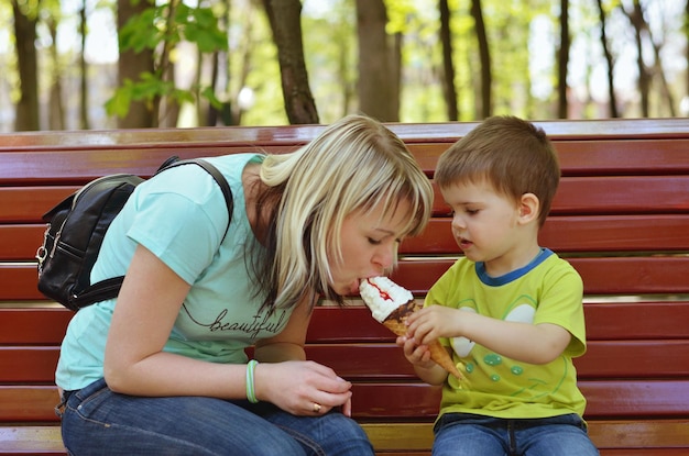 Madre e figlio stanno giocando nel parco giochi, ridendo, divertendosi. Gelato. Felice stile di vita familiare. Ragazzo