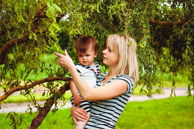 Madre e figlio stanno giocando nel parco giochi, ridendo durante la passeggiata estiva. giorno soleggiato. Vacanza in famiglia. Bambini