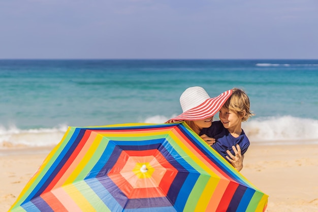 Madre e figlio sulla spiaggia con cappello e ombrellone