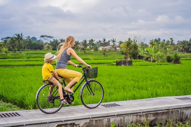 Madre e figlio vanno in bicicletta su un campo di riso a Ubud Bali Viaggio a Bali con il concetto di bambini