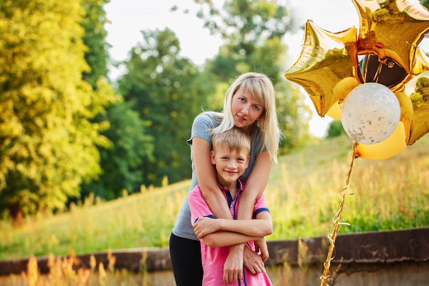 Madre e il suo piccolo figlio con palloncini d&#39;oro in giornata estiva.