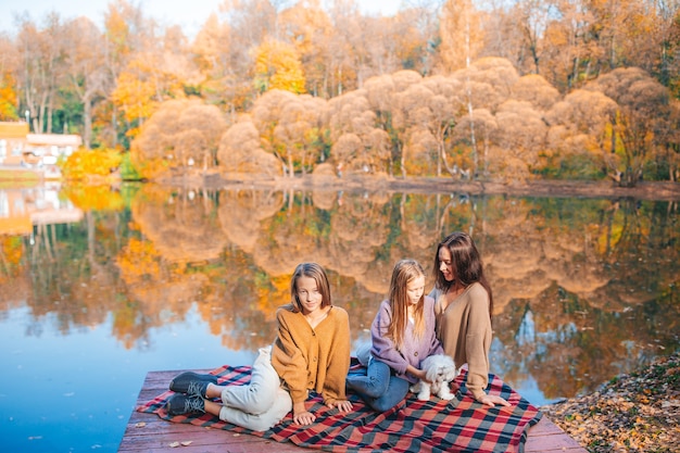 Madre e le sue figlie piccole in autunno sul picnic sul lago