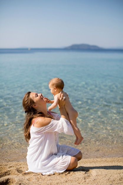 Madre e neonata che si siedono sulla spiaggia