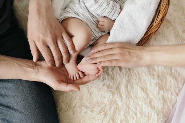 Madre e padre che abbracciano le gambe del loro simpatico neonato