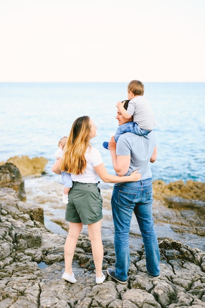 Madre e padre che tengono i loro figli pur avendo una giornata con la famiglia sulla spiaggia rocciosa