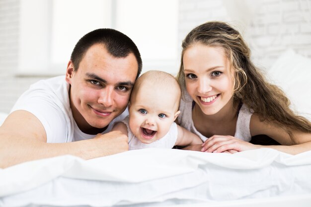 Madre e padre con piccolo bambino in un letto