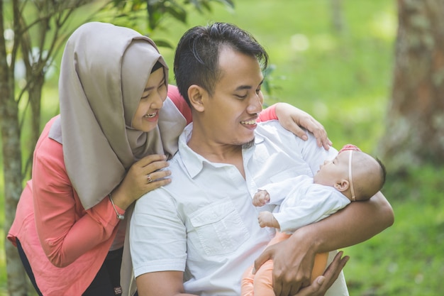 Madre e padre di bellezza con il loro neonato nel parco