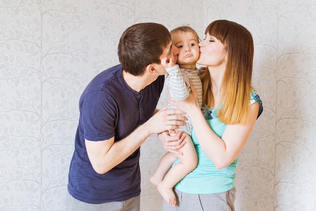 Madre e padre felici che baciano il suo piccolo figlio.