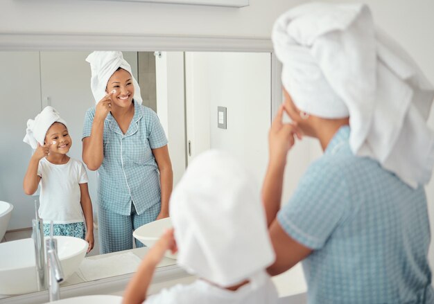 Madre e ragazza che fanno la cura della pelle al mattino in bagno insieme Famiglia nera a casa loro facendo la routine di cura della pelle usando prodotti e lozione sul viso Crema viso e cura del viso per la famiglia