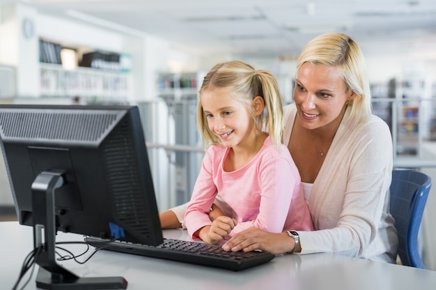 Madre e ragazza che per mezzo del computer