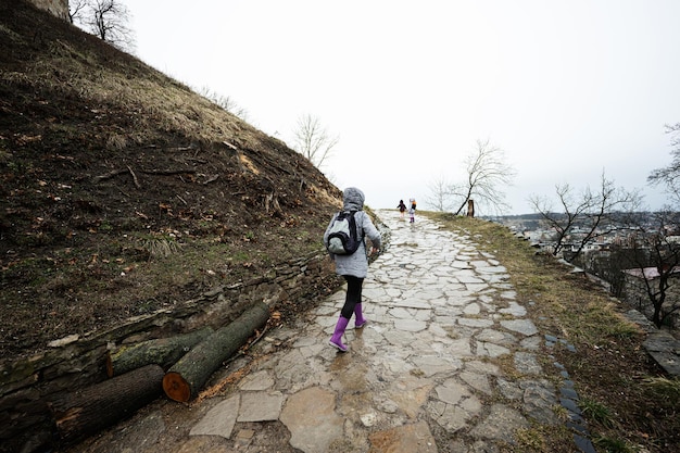 Madre e ragazze camminano lungo il sentiero bagnato fino a un'antica fortezza medievale sotto la pioggia