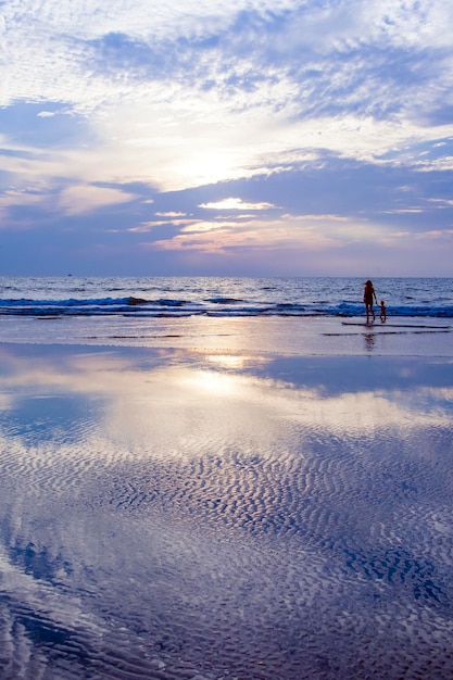 Madre e suo figlio in piedi sulla spiaggia Cielo prodigioso riflesso nel mare