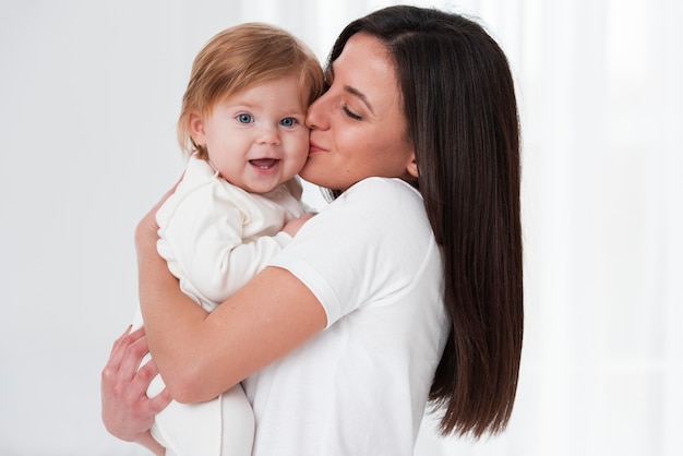 Madre felice che bacia bambino sorridente