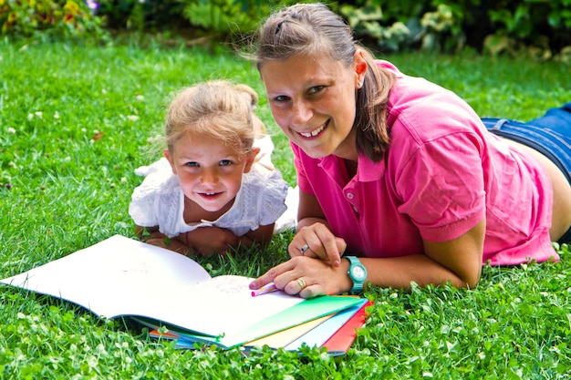 madre felice che disegna un libro con la bambina in giardino