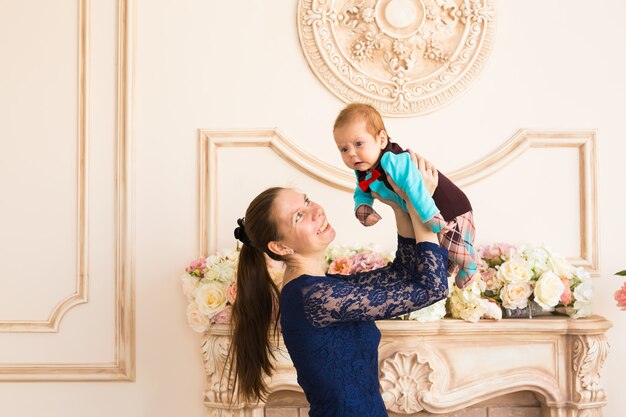 Madre felice che tiene in braccio il suo bambino e gioca con lui in casa