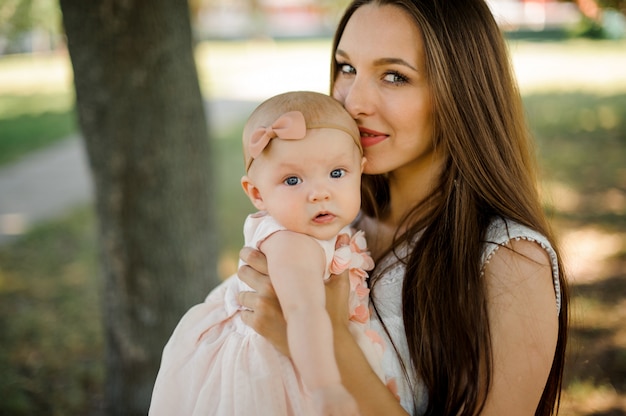 Madre felice che tiene la sua piccola figlia vicino al fronte nel parco