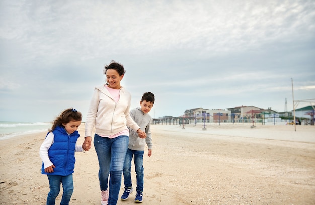 Madre felice con i suoi bambini che camminano sulla spiaggia.