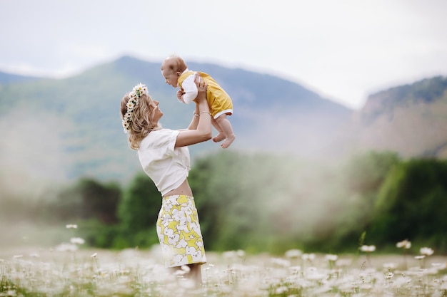 madre felice con il neonato sveglio all'aperto nel campo della camomilla