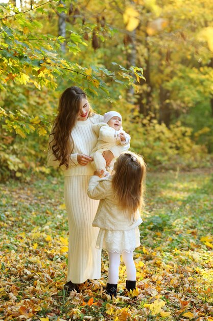 Madre felice con la figlia che si trova sulle foglie di autunno all'aperto
