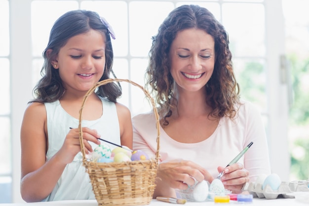 Madre felice e figlia che dipingono le uova di Pasqua