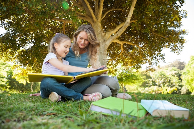Madre felice e figlia che leggono un libro al parco