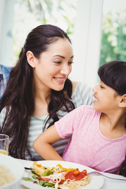 Madre felice e figlia che si siedono al tavolo da pranzo