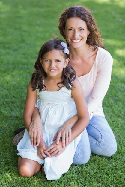 Madre felice e figlia che si siedono sull&#39;erba