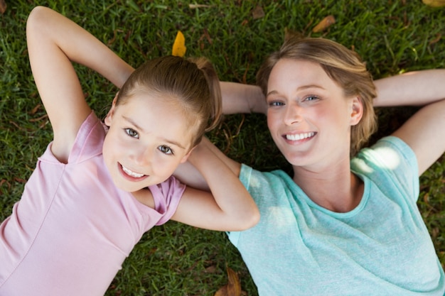 Madre felice e figlia che si trovano sull&#39;erba al parco