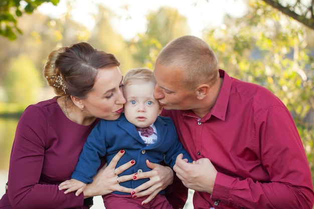 Madre felice e padre bacio figlio nel parco. Felicità nella vita familiare in estate.