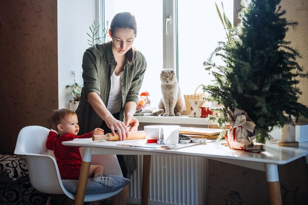 Madre felice e piccola bambina che preparano i biscotti di Natale nella cucina di casa madre e piccola