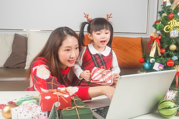 Madre felice e piccola figlia che decorano l'albero di Natale e regali a casa