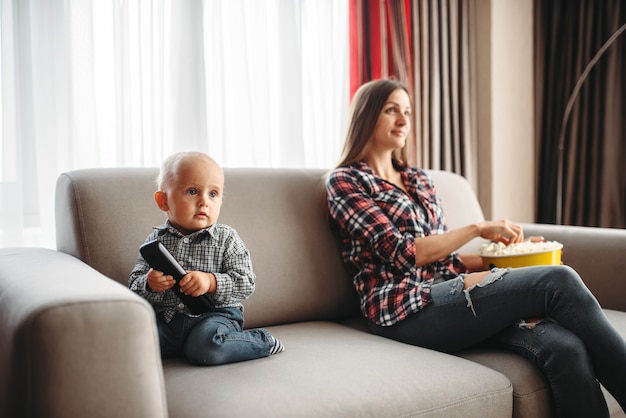 Madre guarda la tv, un ragazzino maschio gioca vicino.