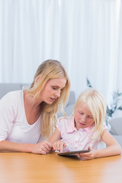 Madre guardando sua figlia utilizzando la tavoletta digitale