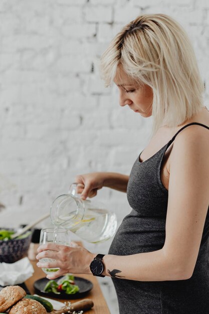 Madre in attesa che versa acqua infusa in un bicchiere