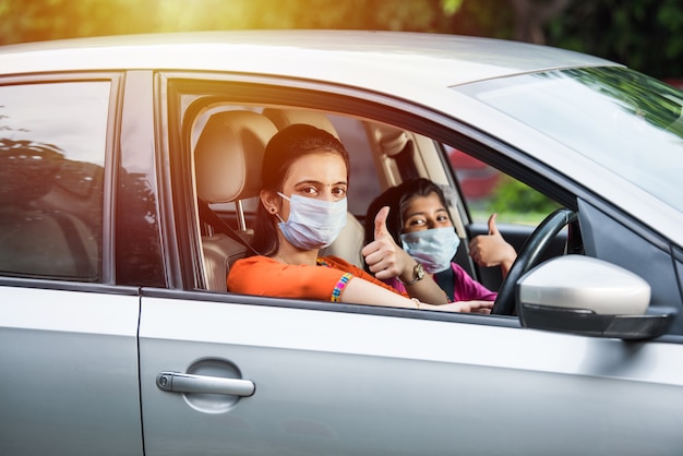 Madre indiana figlia che indossa una maschera facciale o una maschera medica mentre guida l'auto