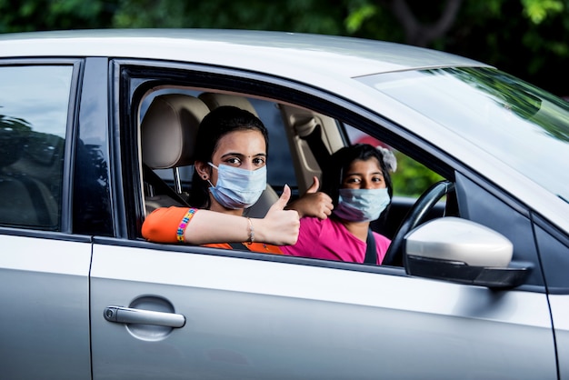 Madre indiana figlia che indossa una maschera facciale o una maschera medica mentre guida l'auto