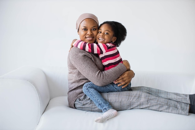 Madre islamica afroamericana in velo seduta in abbraccio con la figlia