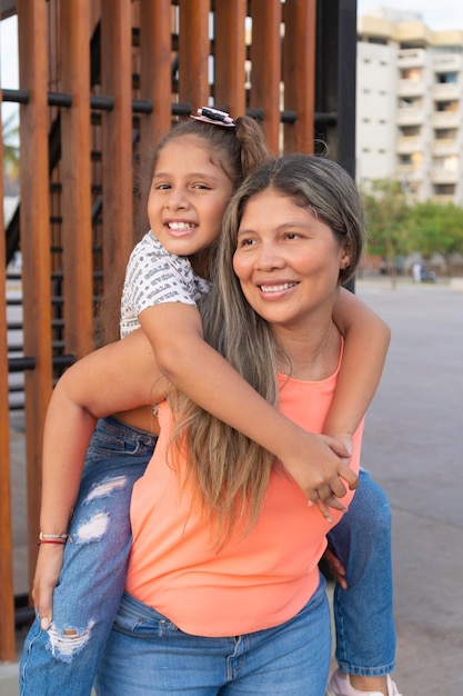 Madre latina che porta sua figlia sulle spalle