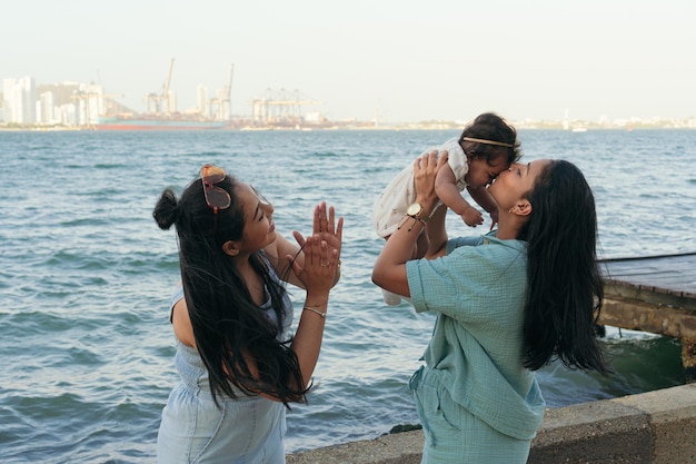 Madre latina con la sorella che solleva in aria il suo bambino