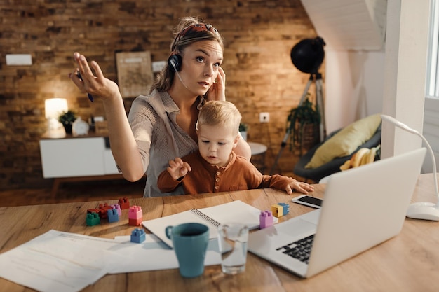 Madre lavoratrice che ha una teleconferenza mentre è a casa con suo figlio piccolo