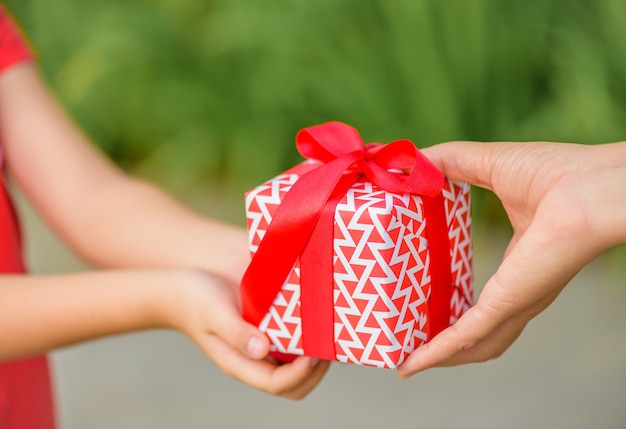 Madre mano dando una scatola regalo al suo bambino. Vacanze, presente, concetto di Natale