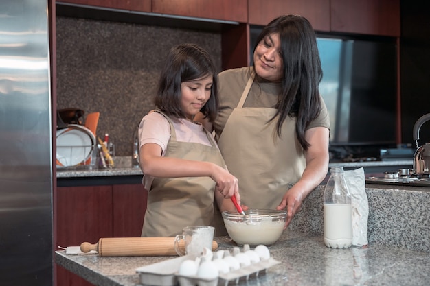 Madre messicana che insegna a sua figlia a cucinare in cucina, la festa della mamma