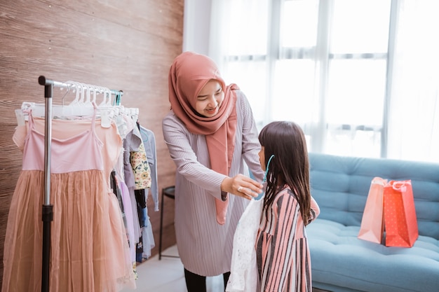 Madre musulmana che fa shopping con sua figlia in un negozio di abbigliamento boutique