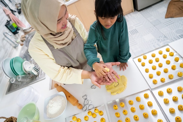 Madre musulmana durante l'attività del Ramadan con sua figlia che prepara una torta nastar insieme